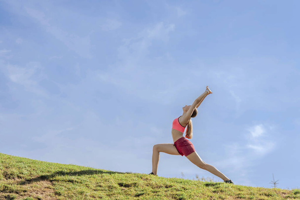 Young lady doing yoga practice on green hill - Fotó, kép