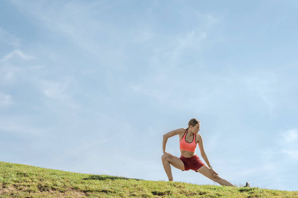 Young lady in yoga pose on green hill - Φωτογραφία, εικόνα