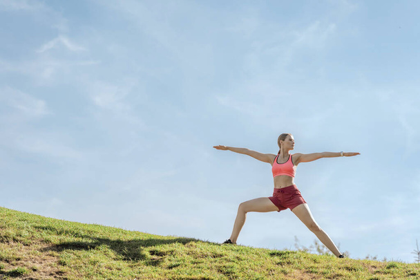 Harmonious lady practicing yoga warrior asana on hill - Foto, immagini
