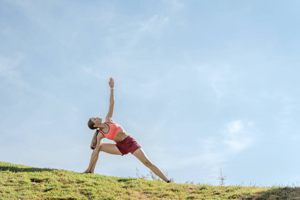 Lady doing yoga exercises on green hill - Φωτογραφία, εικόνα