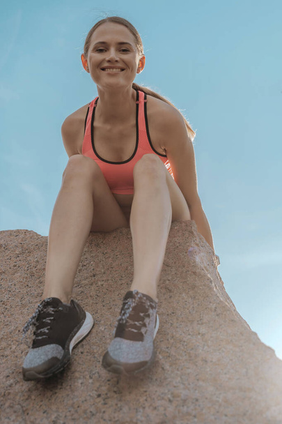 Young happy sportive lady posing on rock ledge - Фото, зображення