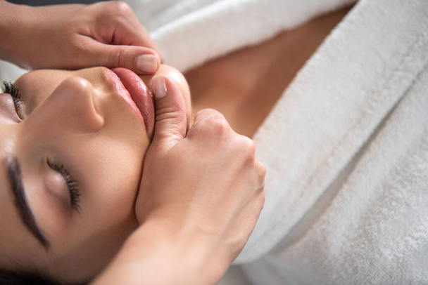 Красива молода жінка отримує масаж обличчя в салоні краси
 - Фото, зображення