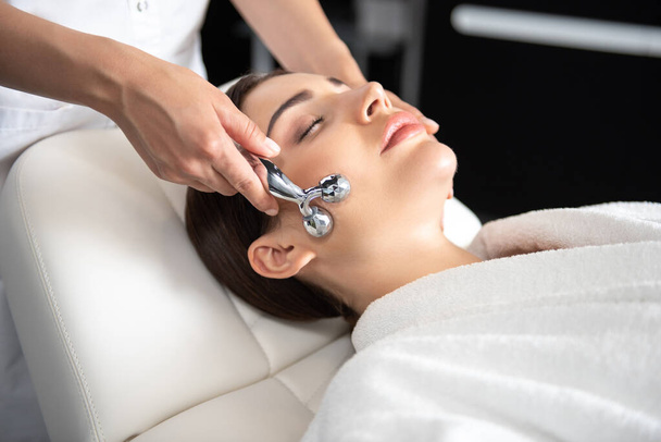 Jovem serena recebendo massagem facial no salão de beleza
 - Foto, Imagem