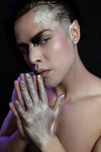 Close up studio portrait of beautiful young man with face art, violet light. - Photo, Image