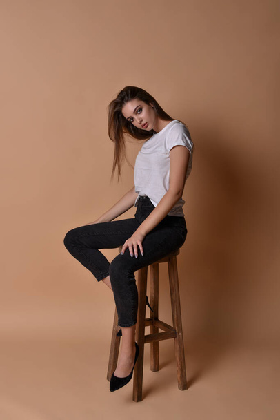 Girl brunette sits on a high bar stool - Foto, imagen