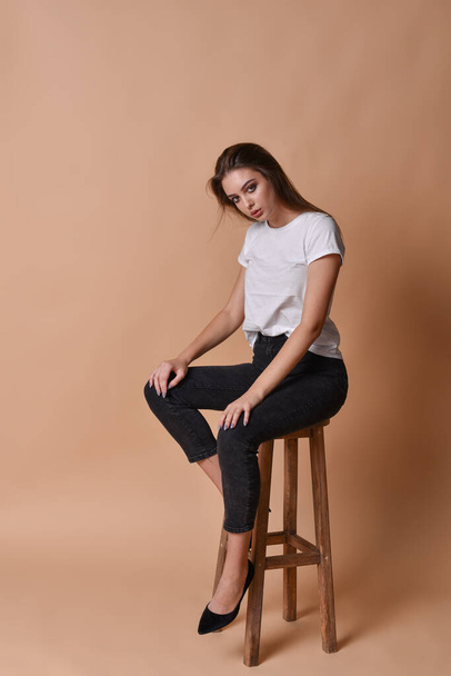 Girl brunette sits on a high bar stool - Фото, изображение