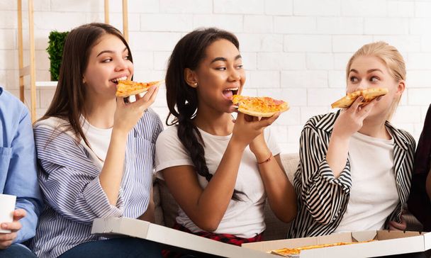 Atıştırma zamanı. Mutlu kızlar pizza yiyip sohbet ediyorlar. - Fotoğraf, Görsel