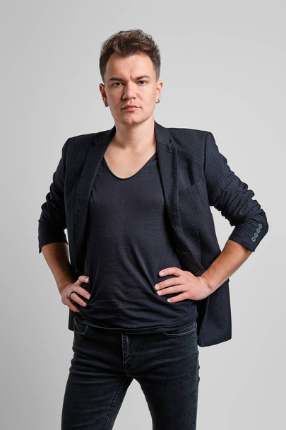 Portrait of serious man in jeans, t-shirt and fitted jacket with hands on waist - Foto, afbeelding