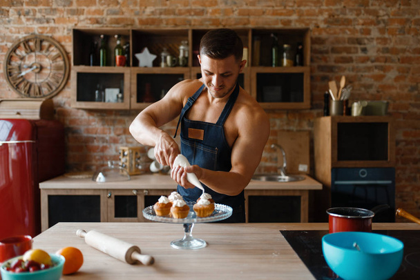 Оголена людина в фартусі готує десерт на кухні. Голий чоловік готує сніданок вдома, гола їжа готує
 - Фото, зображення