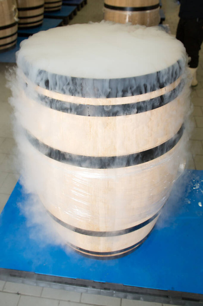wood barrel with red grapes and dry ice smoke in cellar - Photo, Image