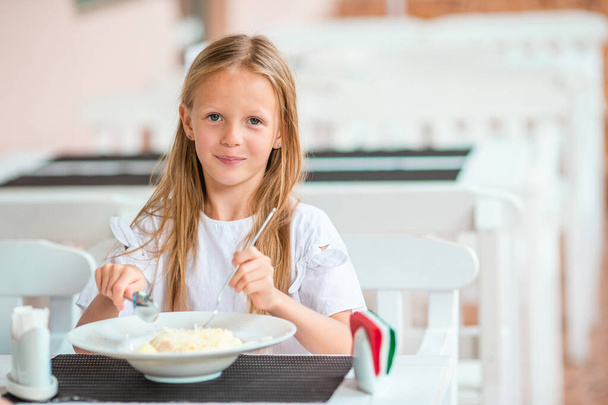 Очаровательная маленькая девочка ужинает в кафе на открытом воздухе
 - Фото, изображение
