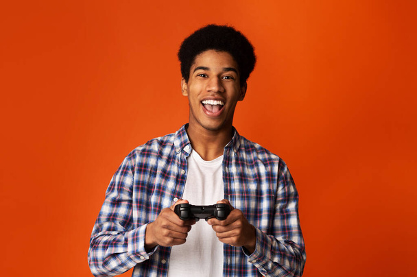 Garoto africano animado segurando joystick e jogando videogames
 - Foto, Imagem