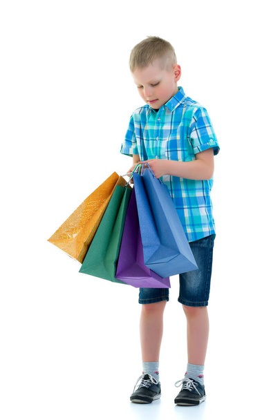 Little boy waving multicolored paper bags. He goes shopping - Fotoğraf, Görsel