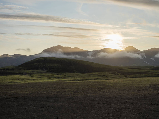 Napkelte Alftavatn kemping területén hóval borított hegyek és zöld dombok és gleccser a háttérben. Nyári táj a Fjallabak Természetvédelmi Terület Izland Felföldjein. Fénymásolási hely. - Fotó, kép