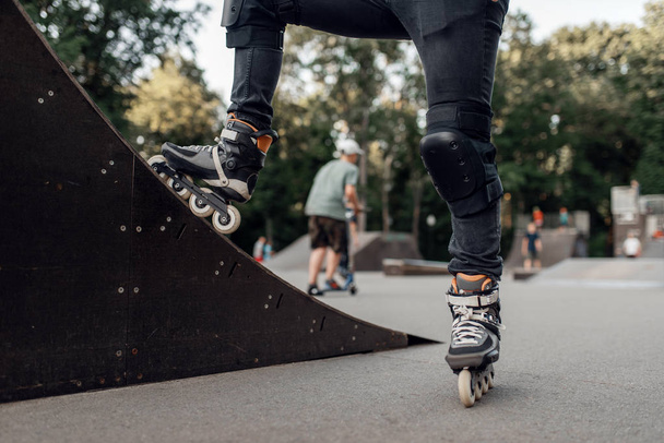 Rolschaatsen, mannelijke schaatser staat op een helling in het park. Stadsrolschaatsen, actieve extreme sport buitenshuis - Foto, afbeelding