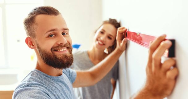 молодая счастливая пара ремонтирует и красит стены в доме
 - Фото, изображение