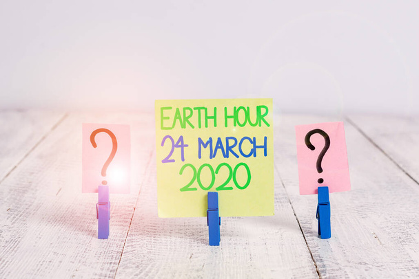 Conceptual hand writing showing Earth Hour 24 March 2020. Business photo text Celebrate Sustainability Save the Planet Lights Off Crumbling sheet with paper clips placed on the wooden table. - Фото, изображение
