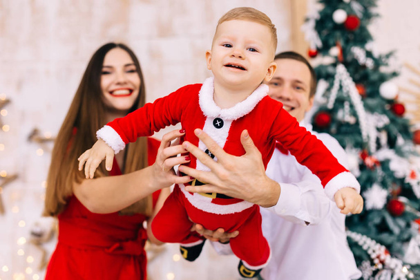 baby flying in santa costume in the foreground. dad and mom hold - Foto, Imagem