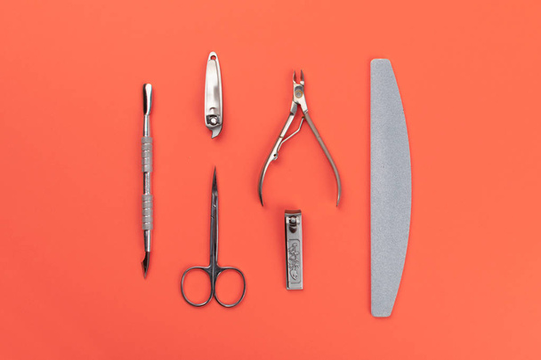 Equipment for cut manicure on coral background. Metal instrument - 写真・画像