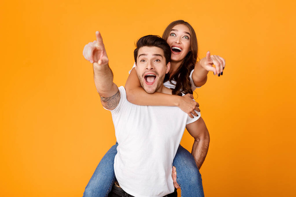 Man giving piggyback ride to woman, pointing fingers at you - Foto, immagini