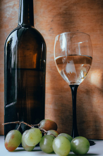 Μπουκάλι κρασιού και γυαλί σε ξύλινο ταμπλό - Φωτογραφία, εικόνα