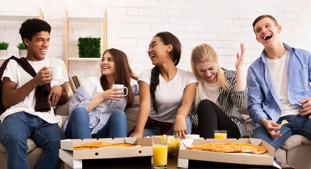 Onnellinen teini syö pizzaa kotibileissä ja juttelee
 - Valokuva, kuva