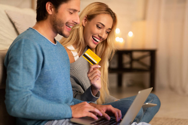 Homem e mulher de compras segurando laptop e cartão de crédito interior
 - Foto, Imagem