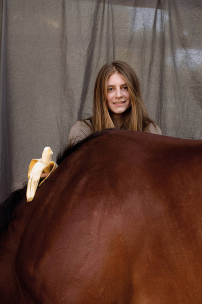 Фото красивая девушка кормит свою лошадь бананами
 - Фото, изображение