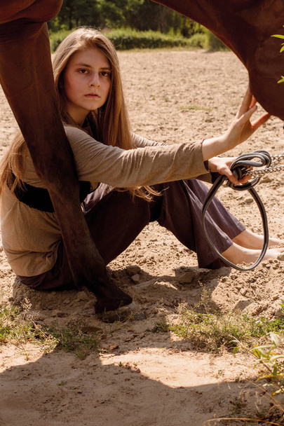 foto menina selvagem de cabelos longos posando ao lado de um cavalo na areia
 - Foto, Imagem