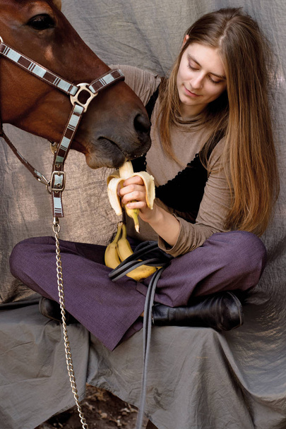 Фото молодая девушка кормит свою лошадь бананами
 - Фото, изображение