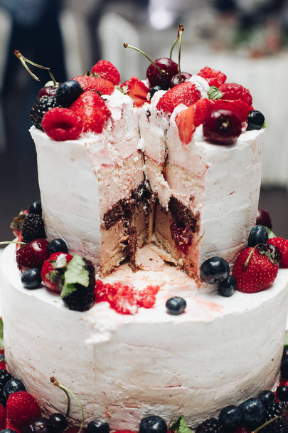Beautiful wedding cake with berries.Sliced wedding cake in close-up. - Photo, image