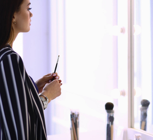 Young woman applying lipstick in front of a mirror - Φωτογραφία, εικόνα