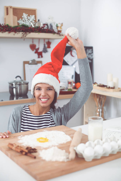 Woman in santa hat making christmas cookies in the kitchen - Fotoğraf, Görsel