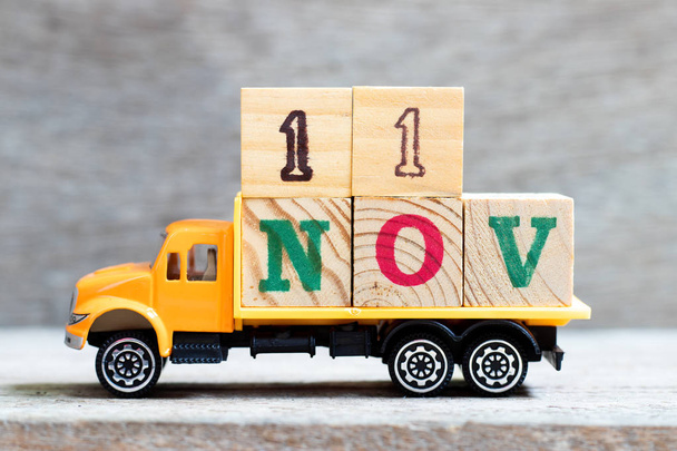 Truck hold letter block in word 11nov on wood background (Concept for date 11 month November) - Photo, Image