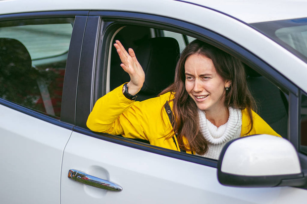 Naštvaná žena čeká v autě na řidiče. Demonstruje gesto skrz okno. - Fotografie, Obrázek