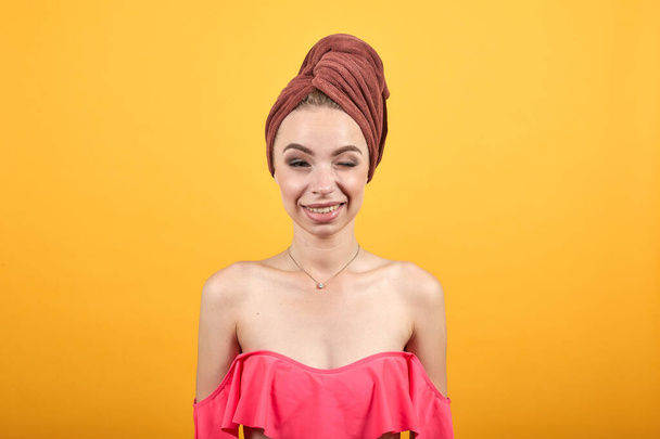 mladá dívka s ručníkem na hlavě přes izolované oranžové pozadí vykazuje emoce - Fotografie, Obrázek