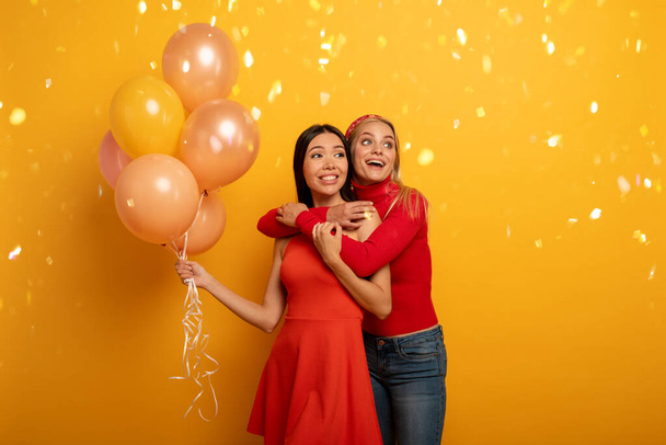 Kızlar balonlu bir partiye hazır. Neşeli bir mutluluk ifadesi. Sarı arkaplan - Fotoğraf, Görsel