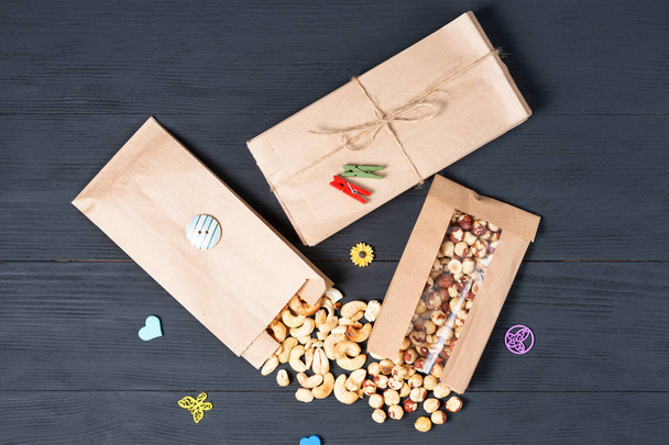 verschillende noten gekonfijte vruchten en gedroogde vruchten op houten ondergrond in eco-verpakking. concept van milieupakketten van recycleerbare materialen - Foto, afbeelding