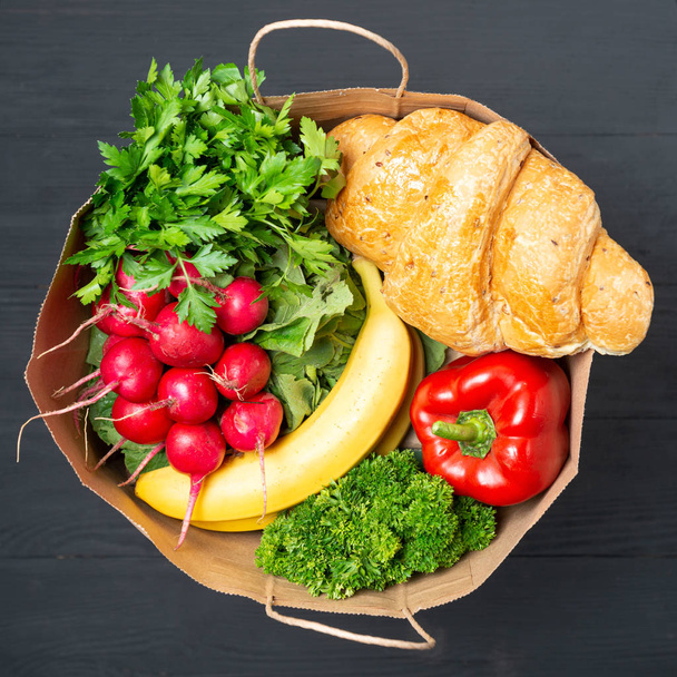 sac en papier complet de divers aliments et légumes avec des fruits sur fond en bois noir. concept de paquets écologiques de matières recyclables
 - Photo, image