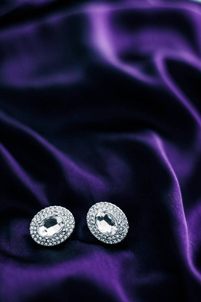 Luxury diamond earrings on dark violet silk fabric, holiday glam - Photo, Image