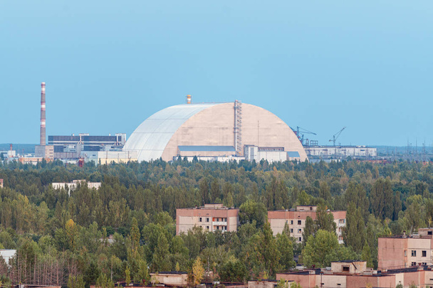 Вид на нову захищену арку на Чорнобильській атомній електростанції через перспективу покинутого Прип'яті. Nsf - це новий саркофаг для безпечної деактивації. - Фото, зображення