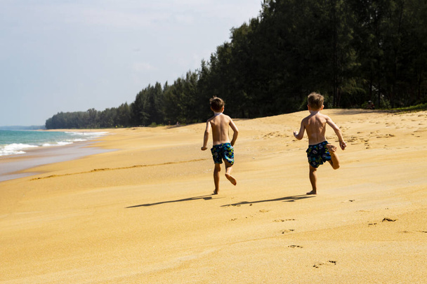 two boys run on a sandy beach - Foto, Imagen