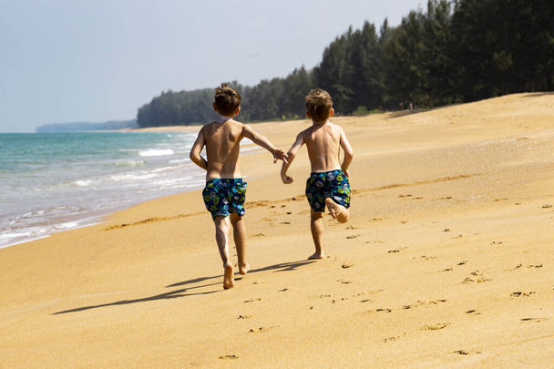 two boys run on a sandy beach - Foto, Imagen