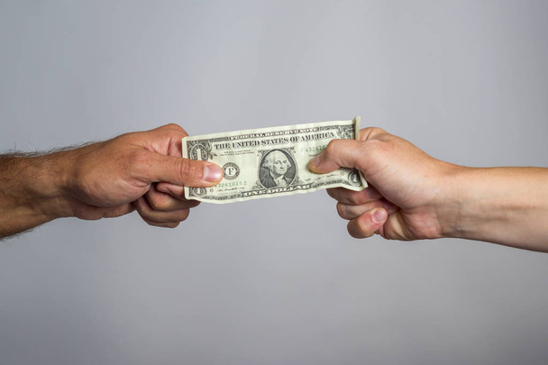 Two hands holding dollar bill. People fighting over money. Financial conflict concept - Photo, Image