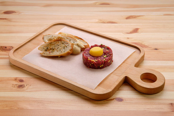 Classic steak tartare with egg and garlic bread - Foto, afbeelding