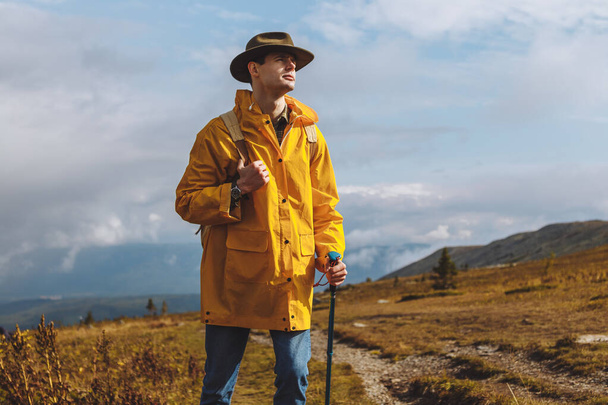 hiker in stylish coat and hat looking at the landscape - Valokuva, kuva
