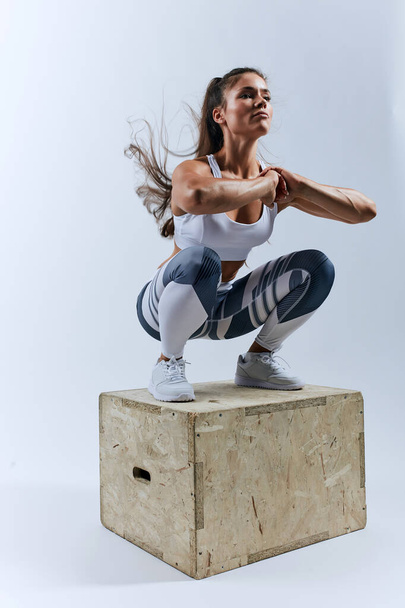 muscular sweaty girl doing squats on the box, keeping fit - Photo, Image