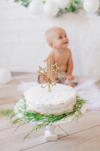 Cute little boy with a birthday cake on his first birthday with white balloons and vintage clothes - Photo, image