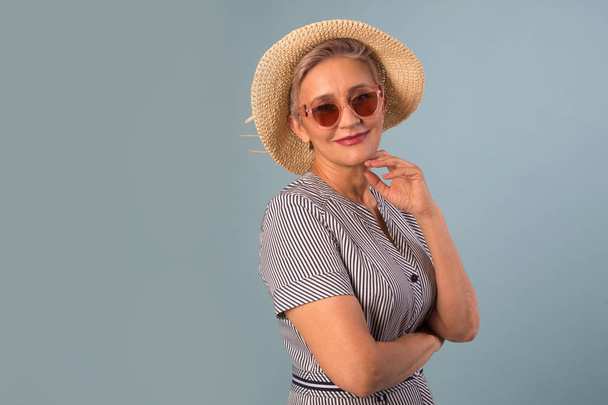 adult elderly woman in a hat on a blue background in sunglasses - Foto, immagini
