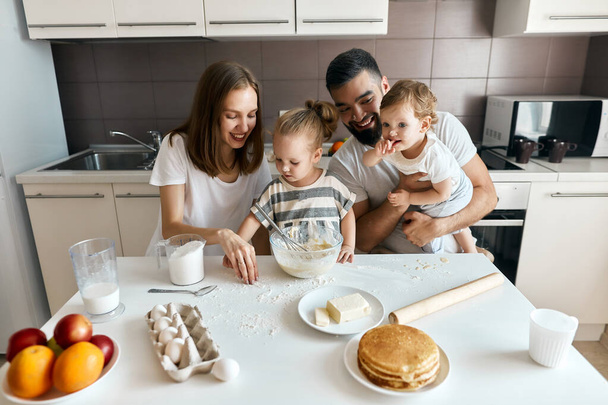 funny family with dirty faces picking flour which is luing on the table - 写真・画像
